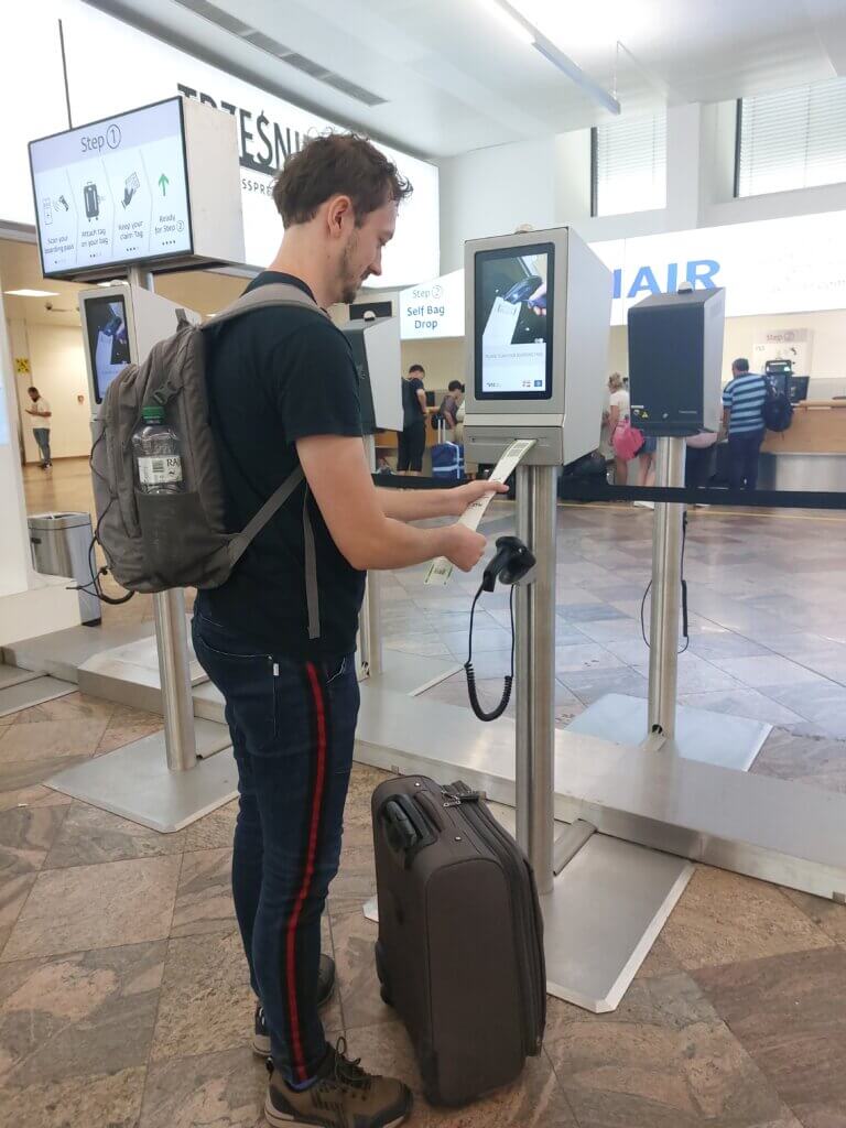 Daniel getting a label for luggage from the self-service baggage drop-off machine at the airport