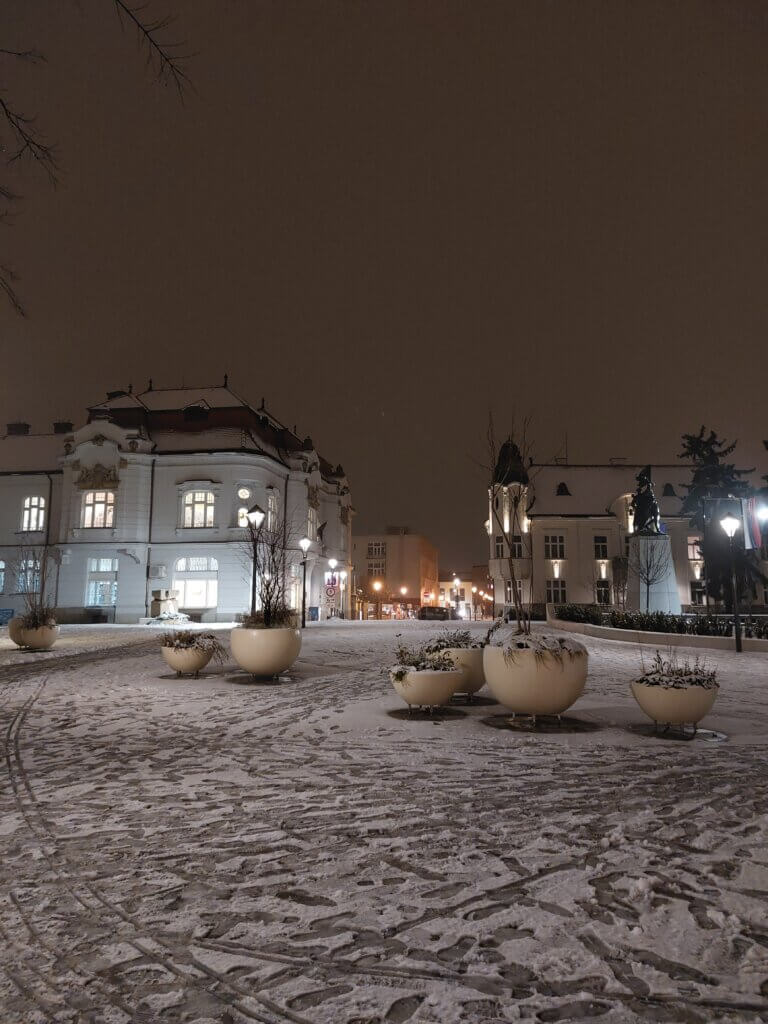 Two historical buildings with beautiful architecture and a dusting of snow all around.