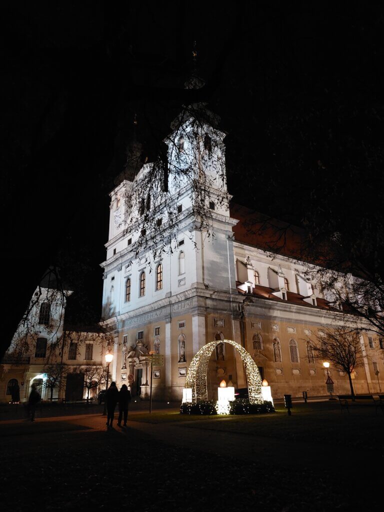 A night time shot of a lit up cathedral with a giant Advent wreath in front of it.