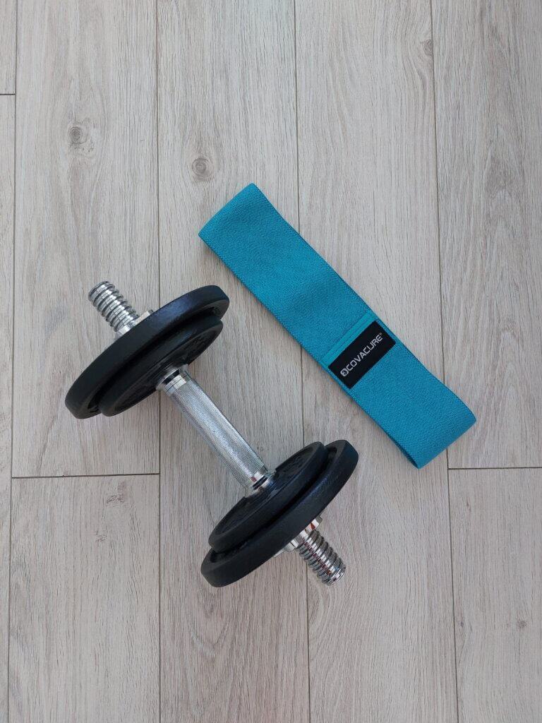 A dumbell and a resistance band sitting on wooden floor