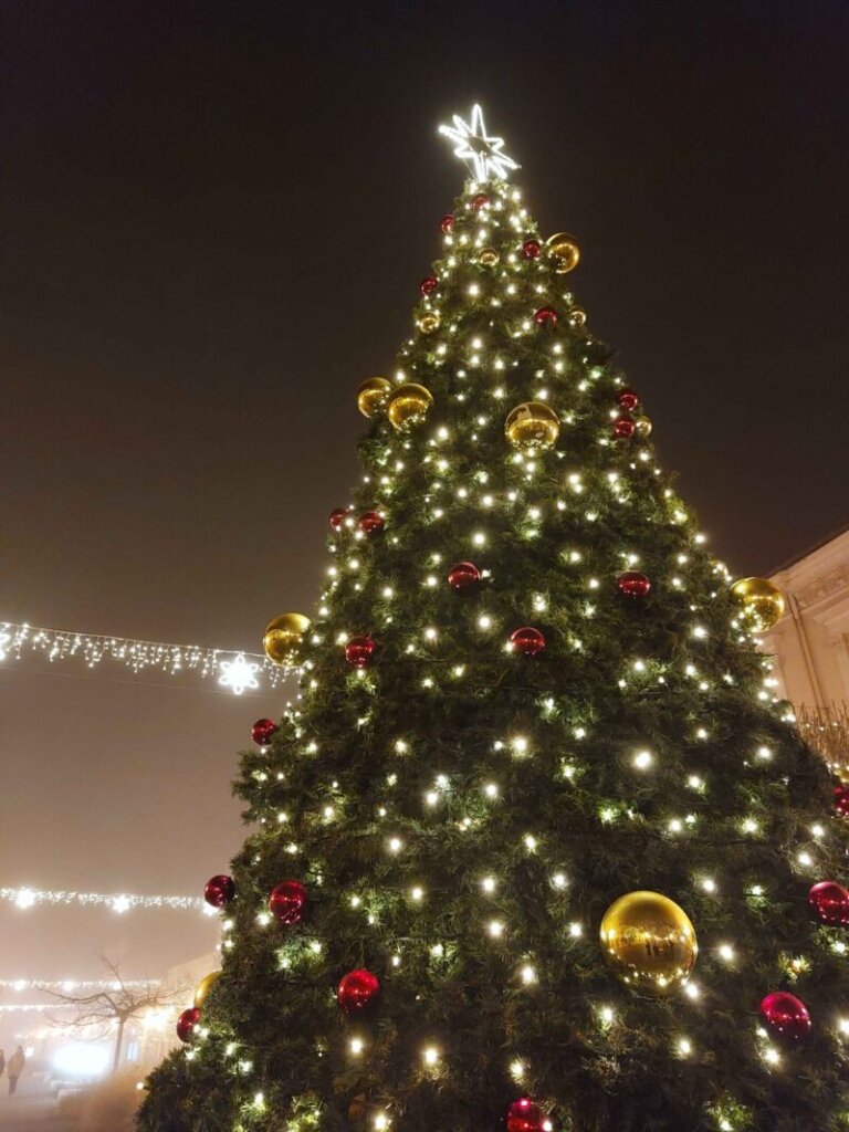 A foggy pedestrian zone with a massive Christmas tree in the foreground