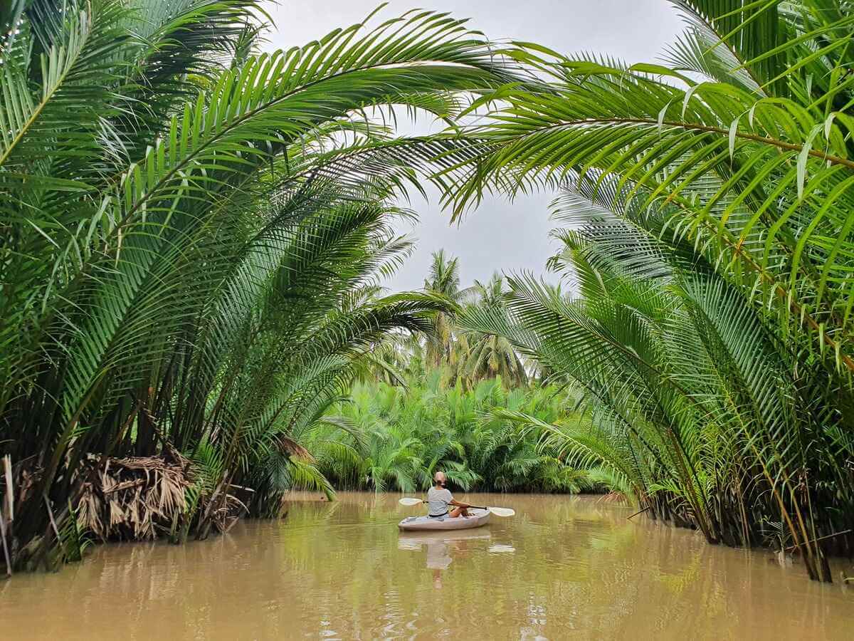 Mirka sitting in a kayak beneath overhanging palm trees