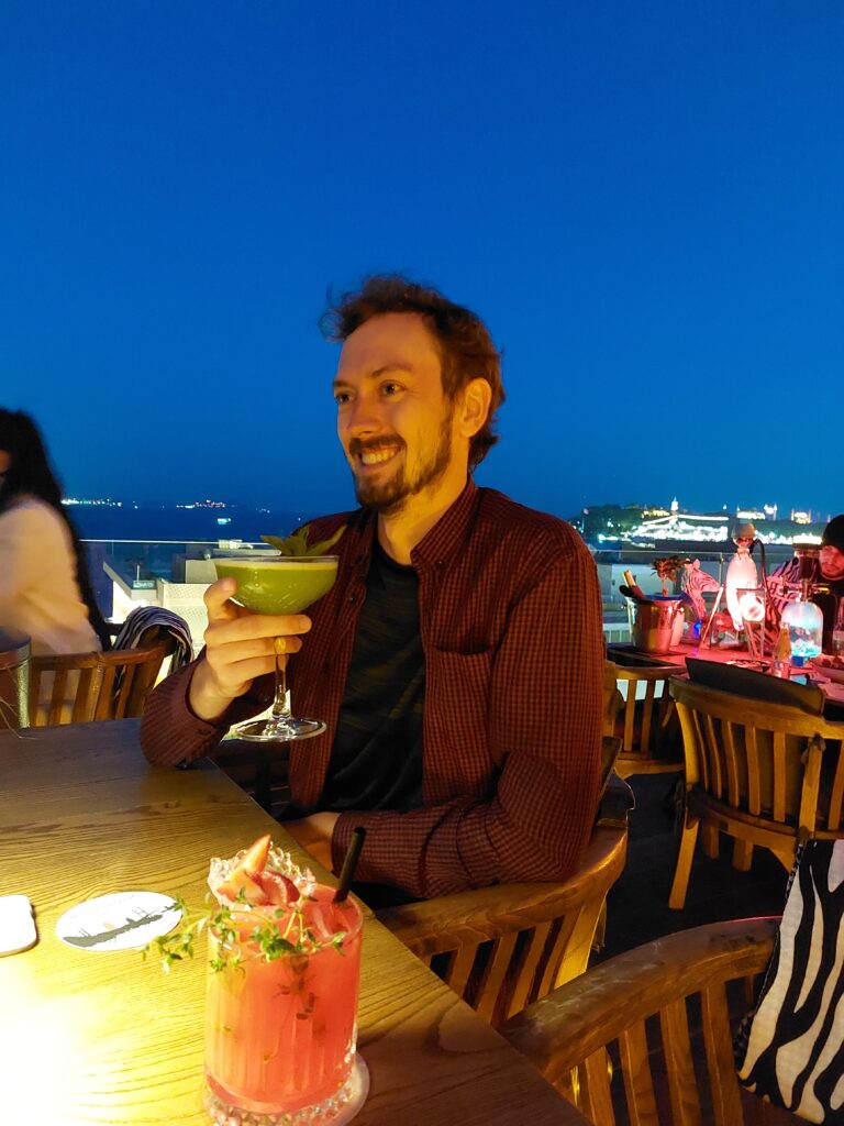 Daniel with a cocktail in hand in a rooftop bar in Istanbul