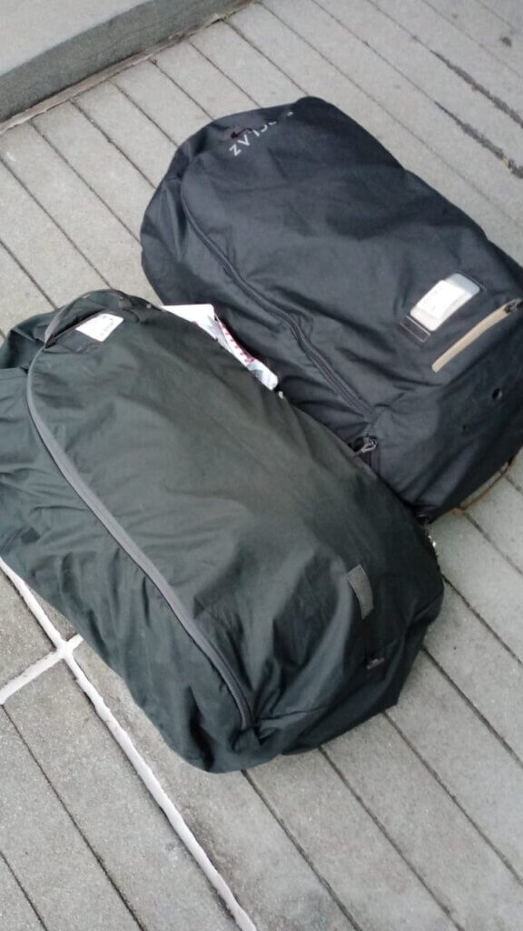 two big backpacks lying on the ground in their backpack covers.