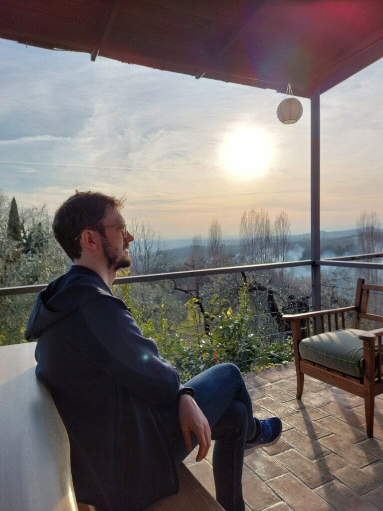 Daniel sitting on a terrace overlooking the Italian countryside while volunteering