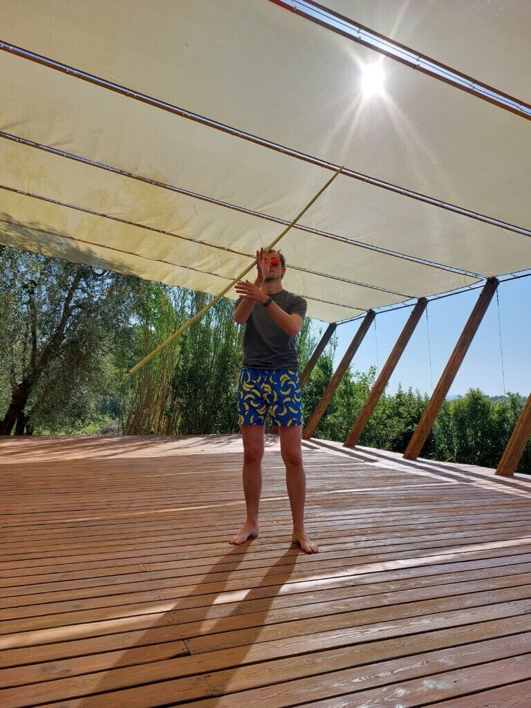 Daniel standing on a big wooden platform practising martial arts with a bamboo stick