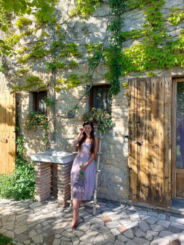 Mirka posing in front of an Italian country house holding a bouquet of flowers