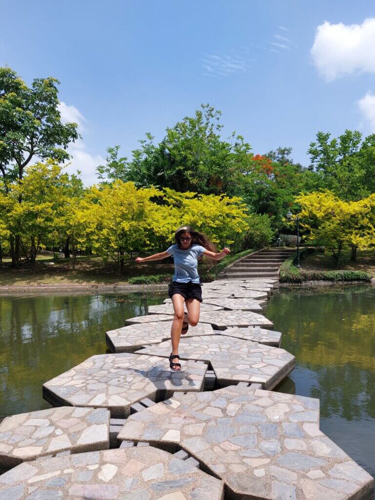 Mirka jumping across a stone bridge in the Queen Sirikit Park