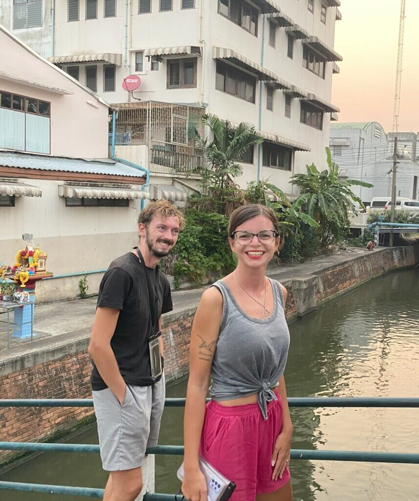 Mirka and Daniel standing next to a canal in Bangkok during Songkran. Daniel has a waterproof phone case around his neck and Mirka is holding hers in her hand
