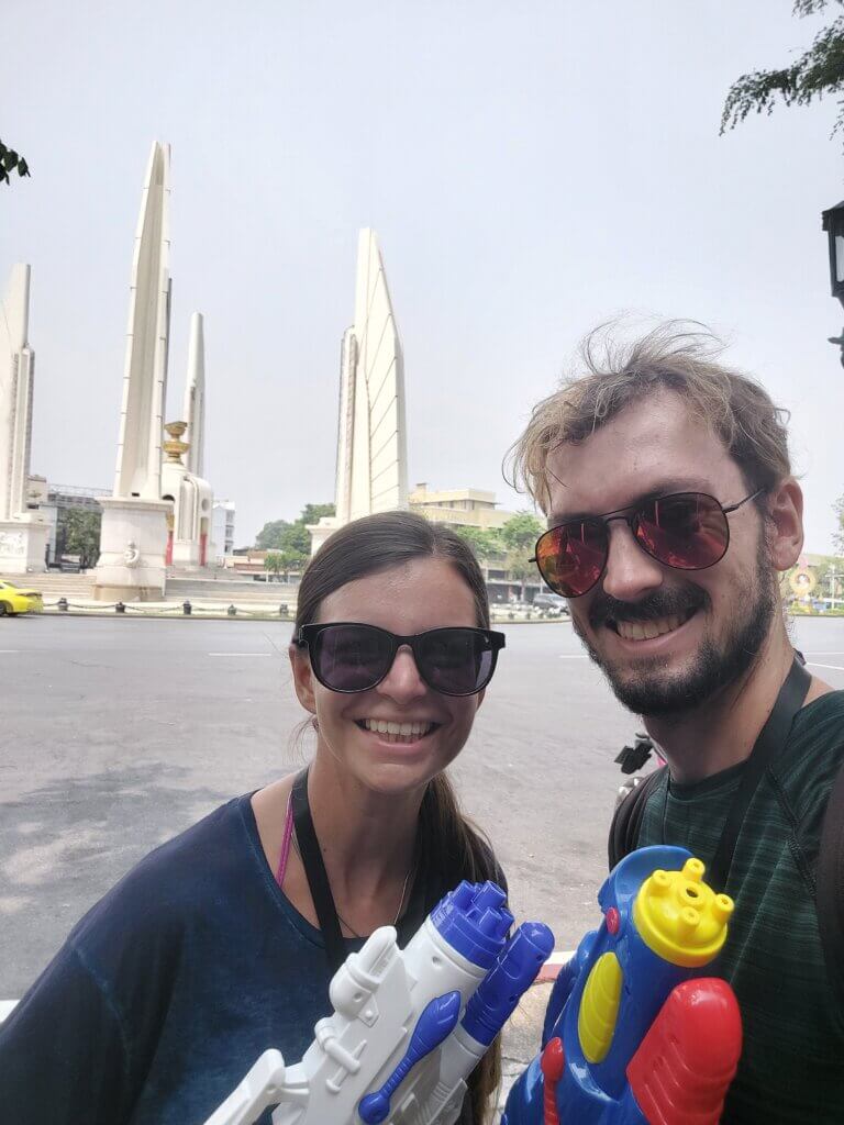 Mirka and Daniel taking a selfie in front of the Democracy Monument in Bangkok, holding up water guns