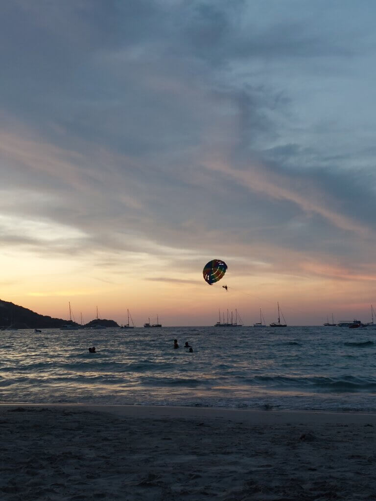 Parasailing person above the sea in Phuket during sunset