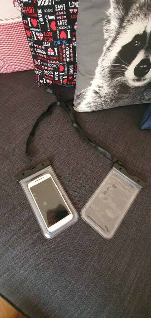 two waterproof phone cases lying on a black sofa, one has a white phone inside