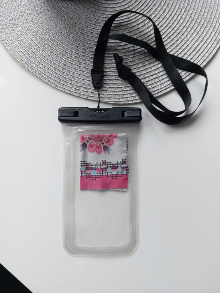 a clear waterproof phone case with a pink and white floral cloth for cleaning glasses inside