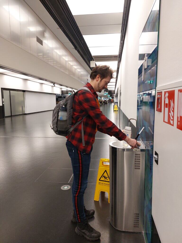 Daniel topping up a water bottle at at an airport from a water fountain