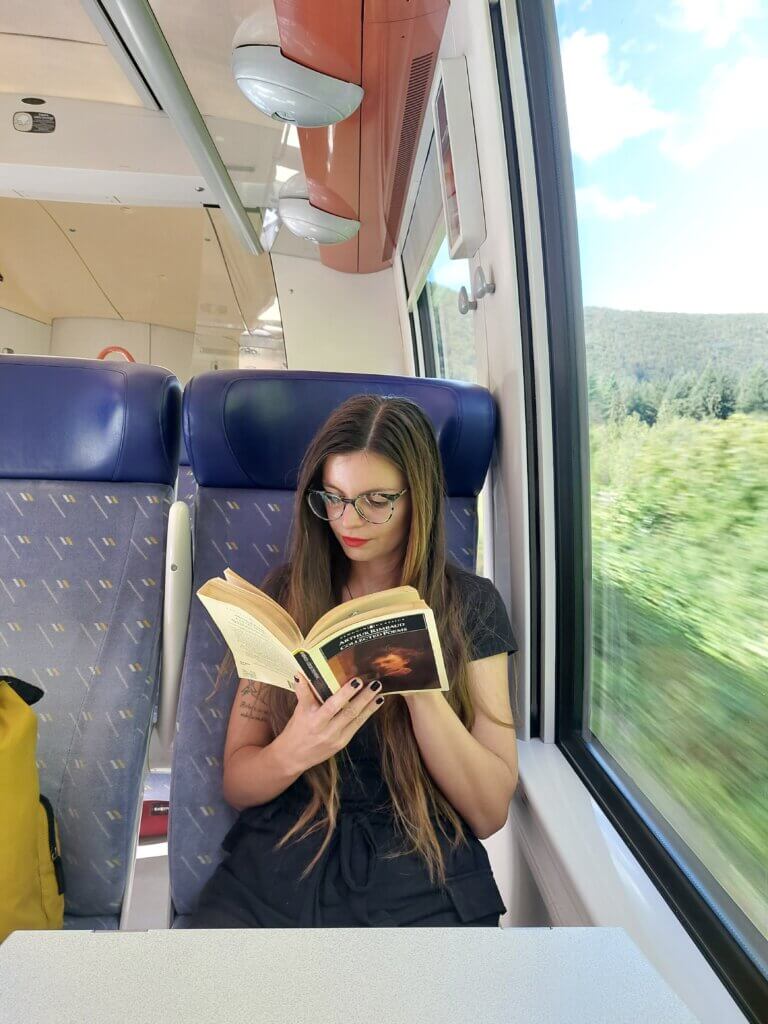 Mirka sitting on a train, reading a book