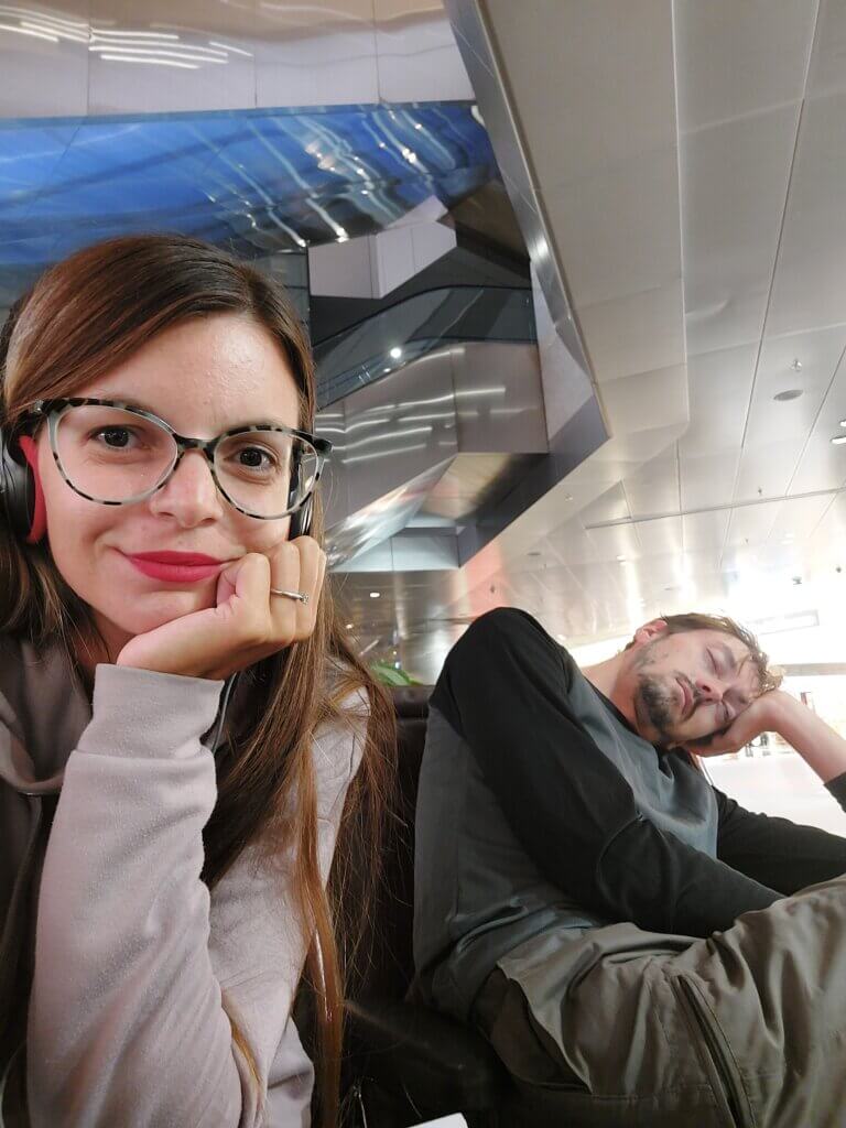 One of our crazy travel habits - sleeping at airports. A selfie of Mirka with Daniel sleeping next to her
