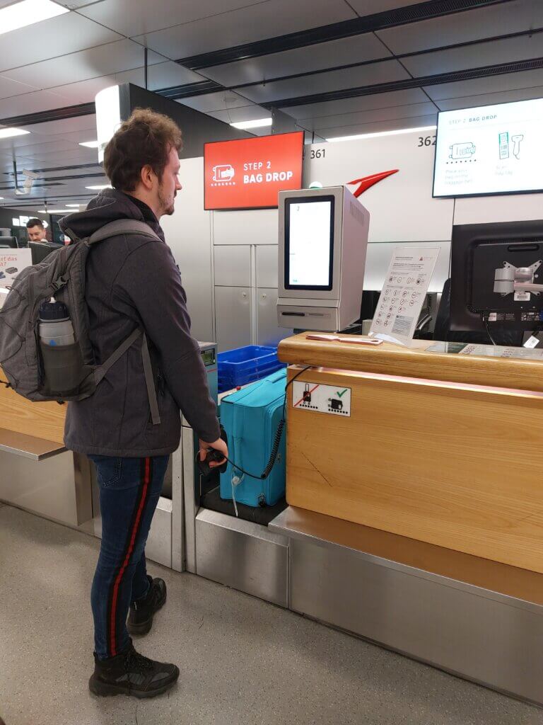 Daniel standing at the self-service bag drop off at an airport