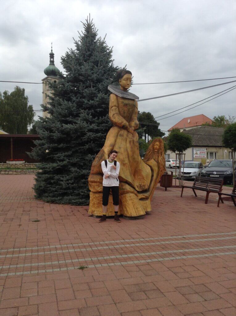 Daniel standing in front of a big wooden statue of countess Bathory, pretending to be a vampire
