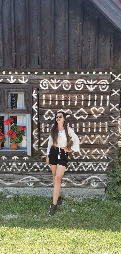 Mirka standing in front of a folkore-painted house in the village Cicmany