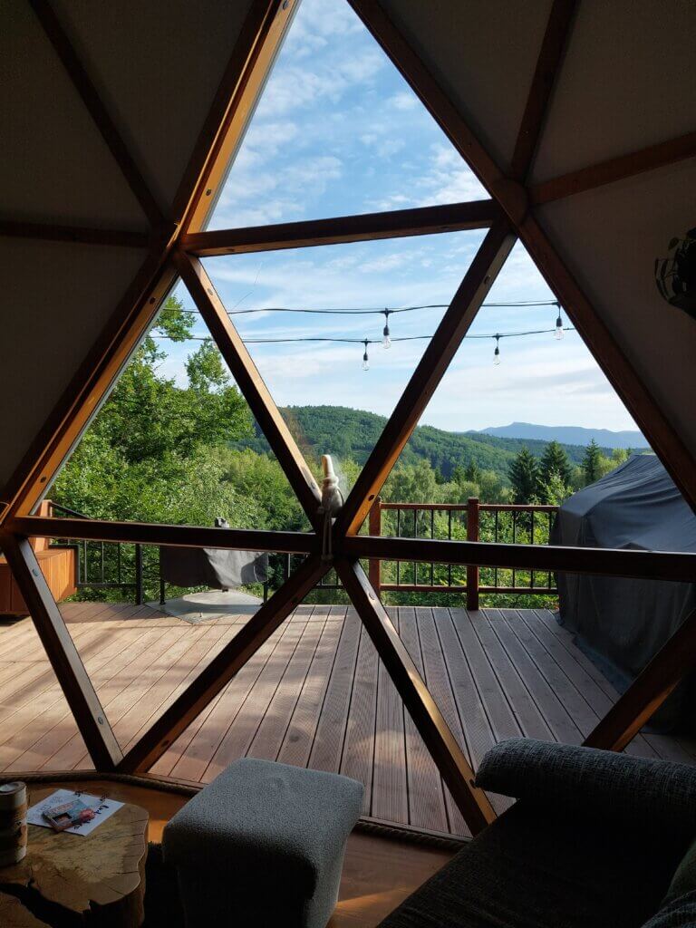 Inside-out shot, geodome's front glass wall and the trees and mountains behind