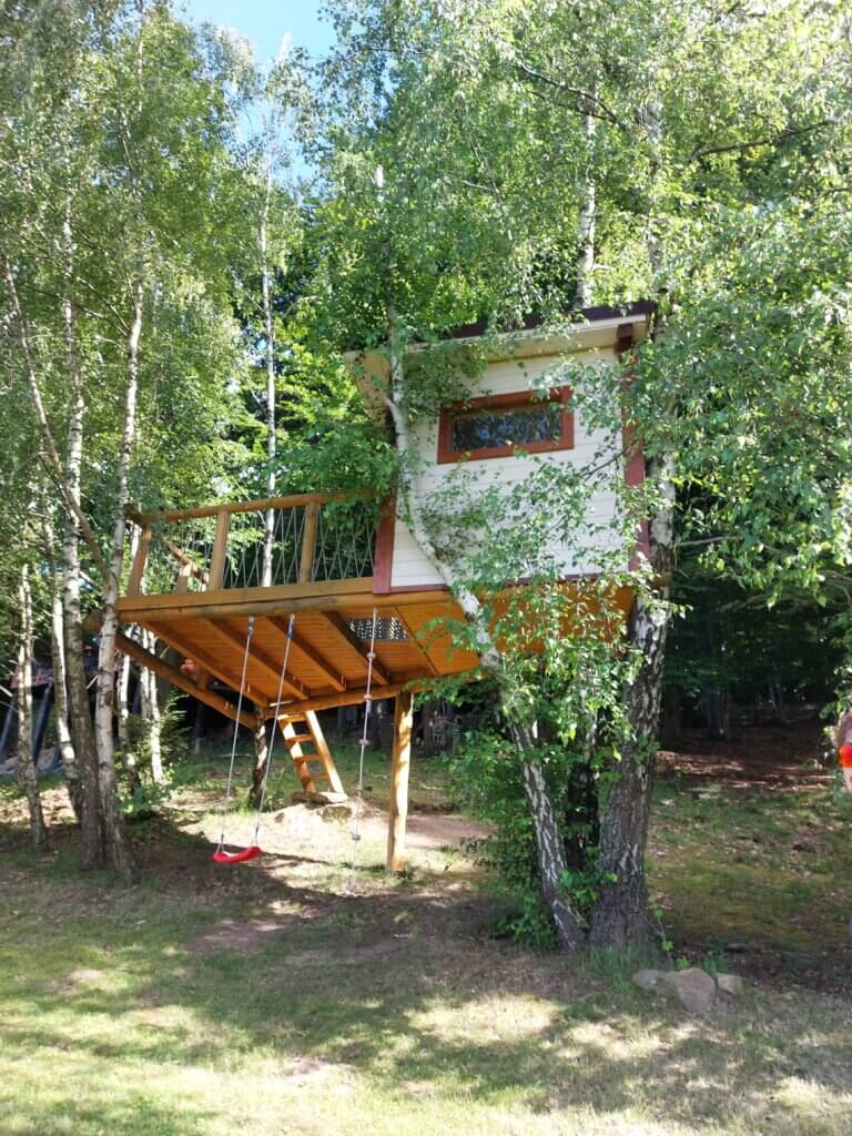 A treehouse and two swings hanging from it