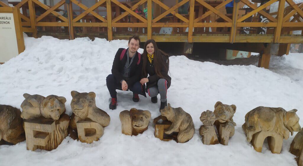 Mirka and Daniel posing behind a row of wooden bears