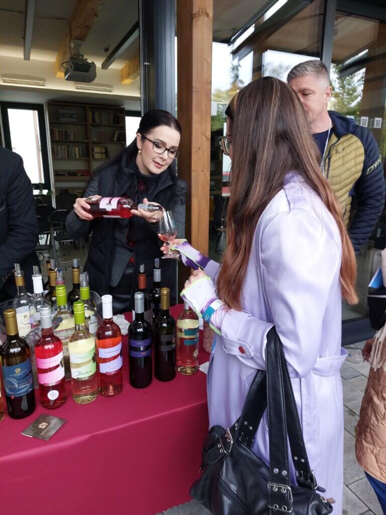 Mirka getting wine poured into her glass by a woman at one of the wine stalls