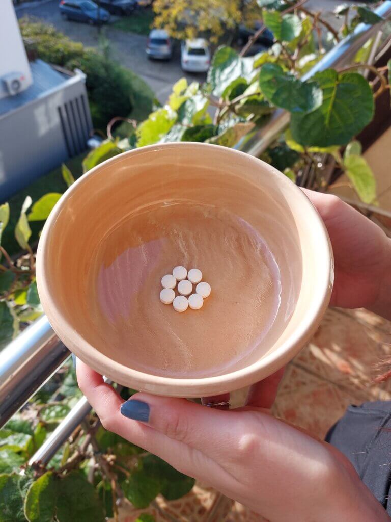 Mirka holding a ceramic bowl with white round tablets arranged in a flower-like shape