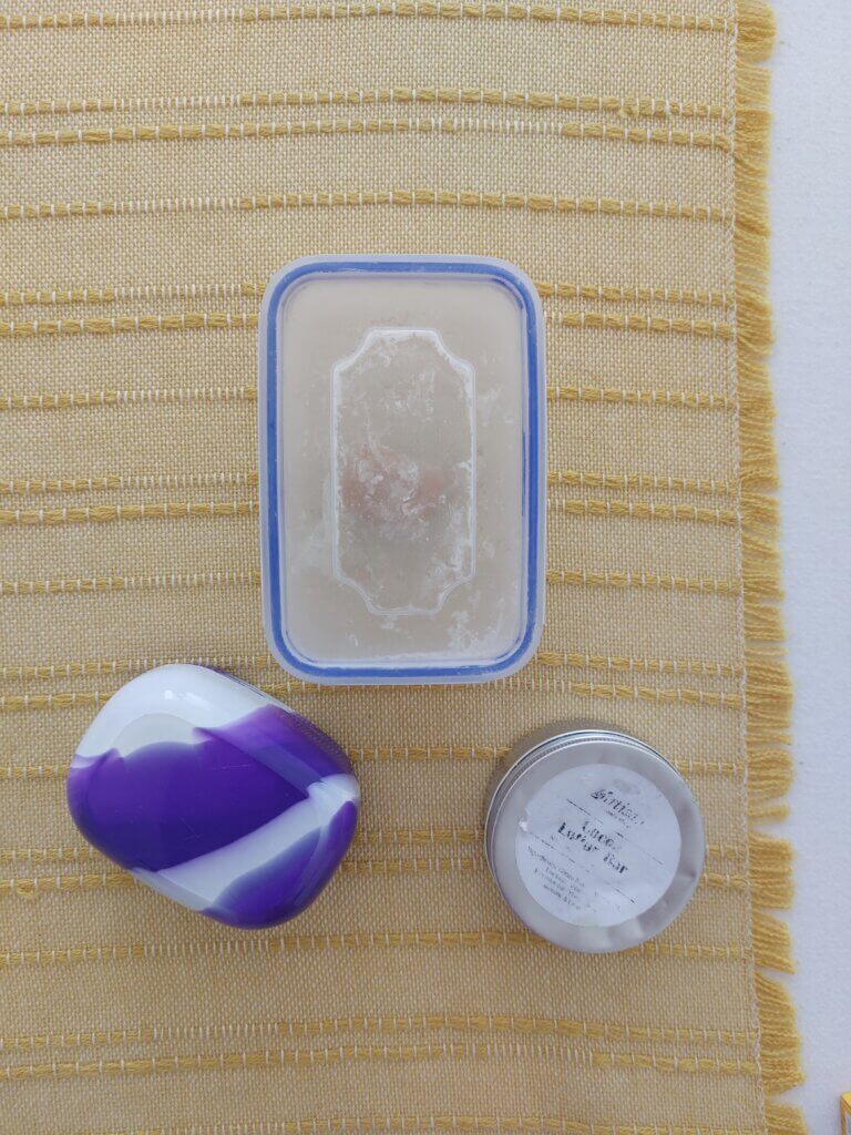 A plastic tub, a soap box and a tin lying on a bed
