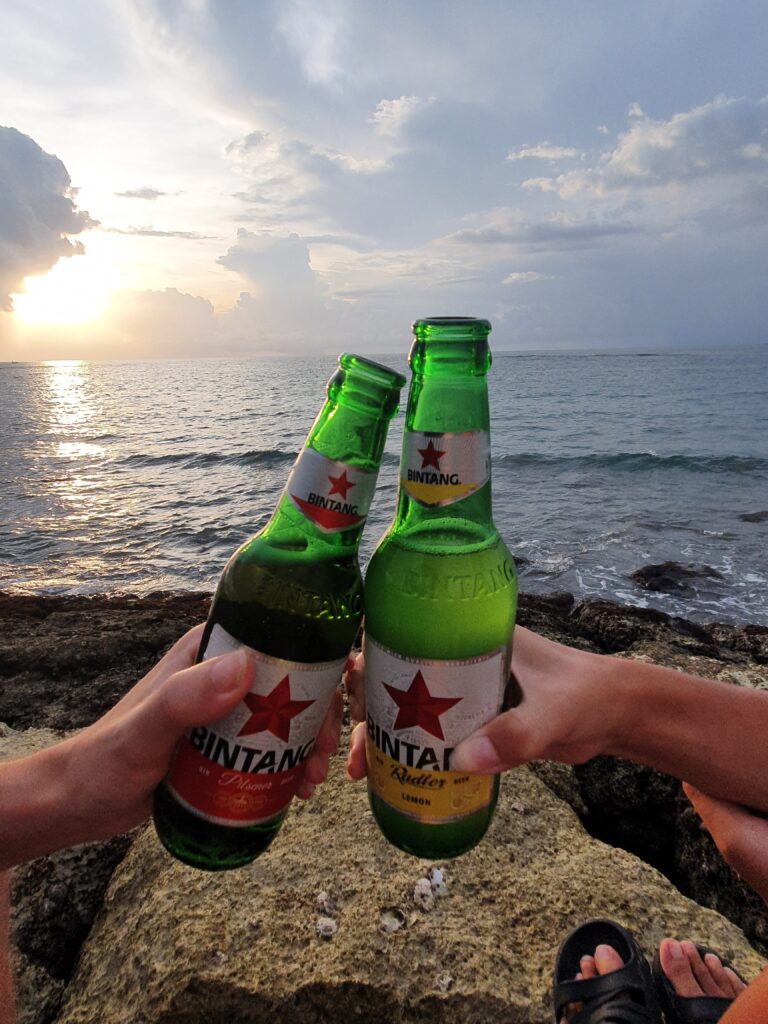 Cheers with two bottles of Bintang with the sea in the background