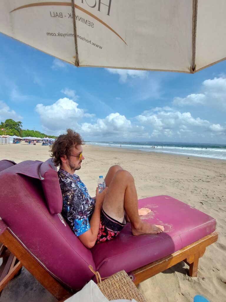 Daniel sitting on a sun lounger on a beach