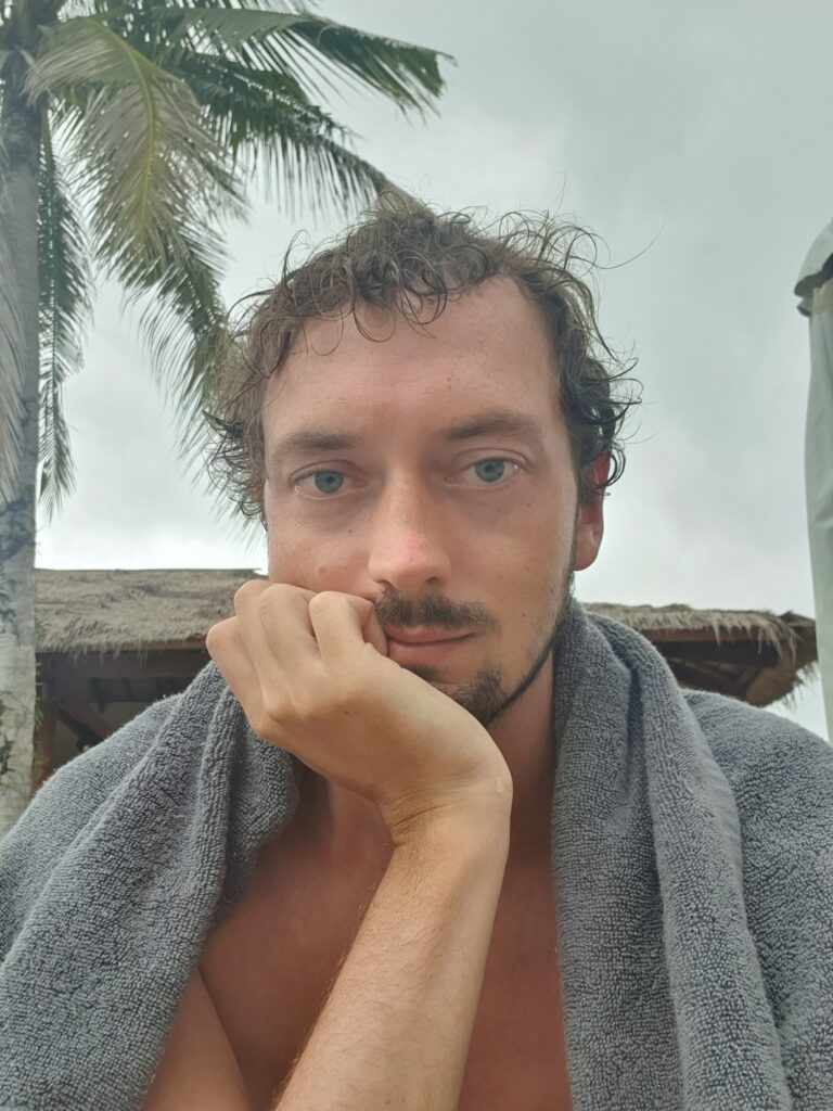 Sad-looking Daniel with an overcast sky and a palm tree behind him