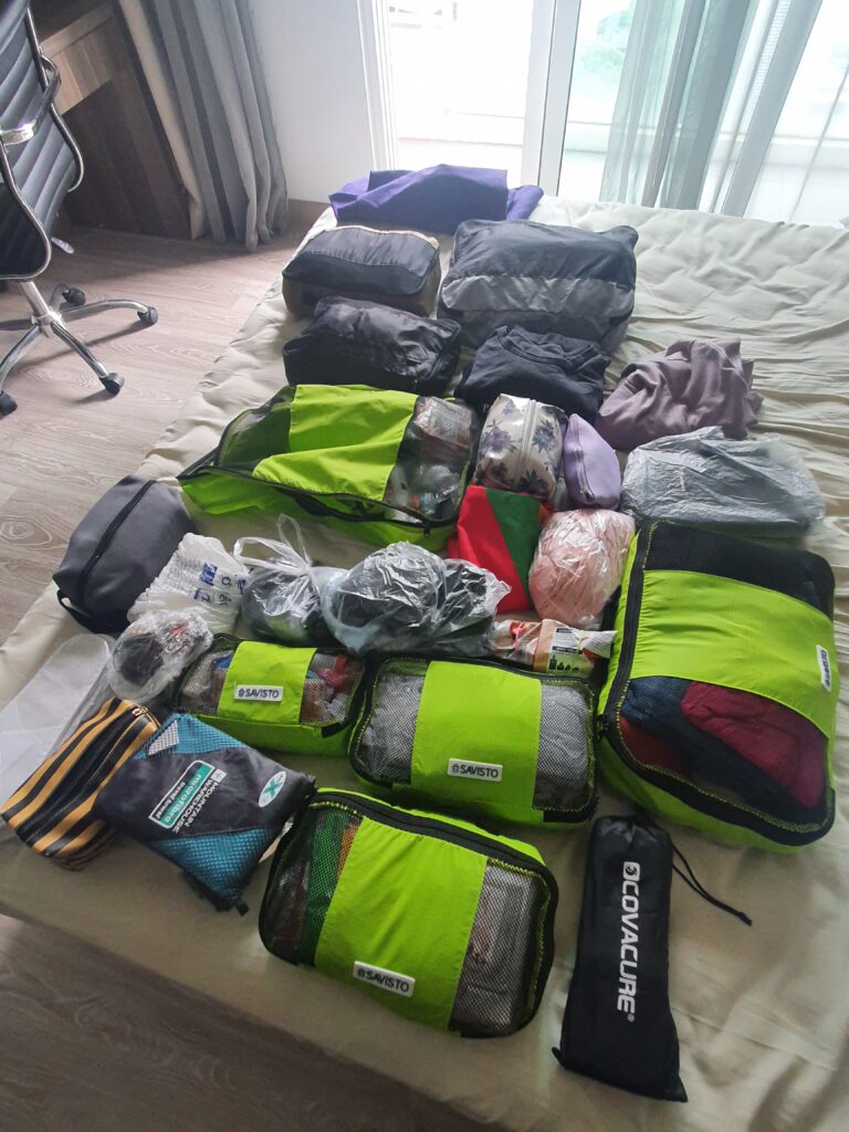 Packing cubes and other assorted bags laid out on a bed