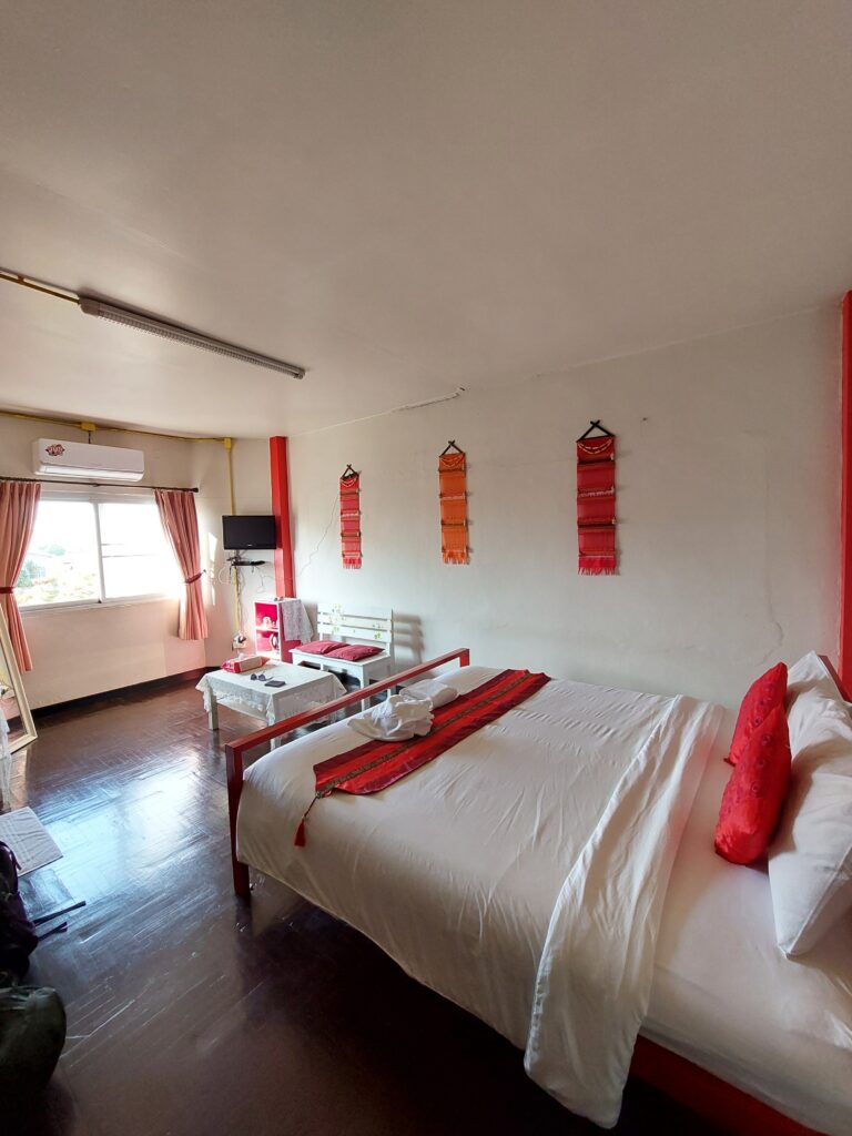 A private hostel room with a bed, window and a double chair