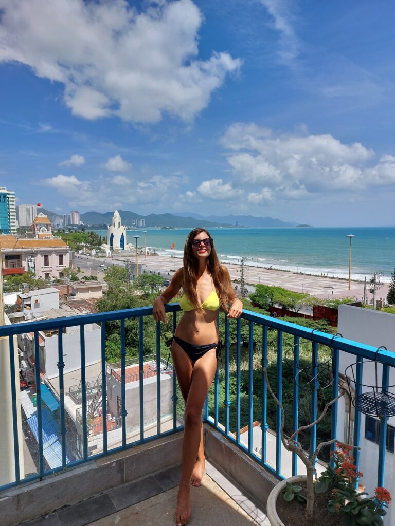 Mirka posing on a terrace with sea behind her