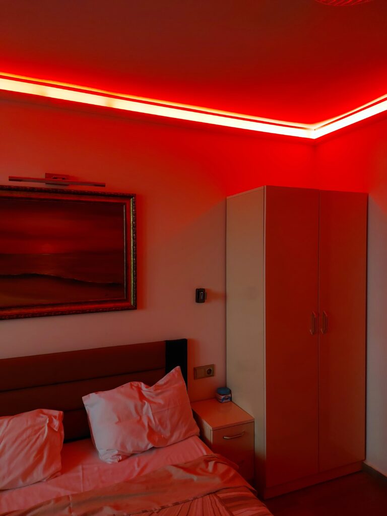 A bed with red LED light strip above it