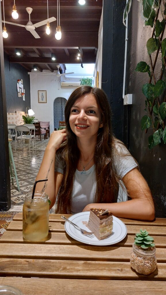 Mirka sitting in a cafe with a crepe cake