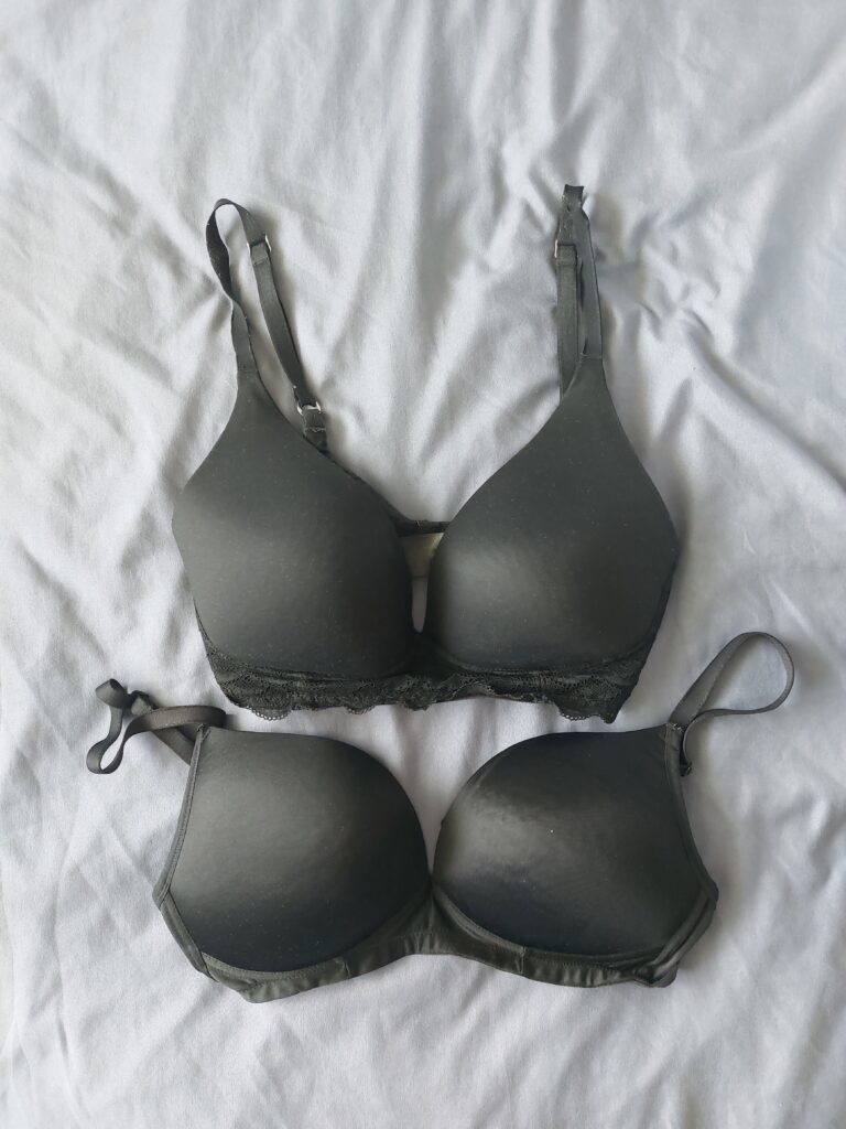 Two black non-wired bras on a bed