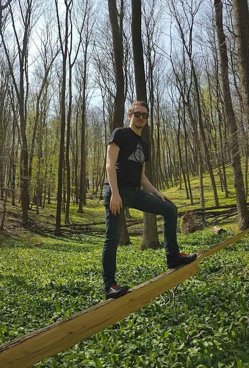 Daniel standing on a broken tree in a forest