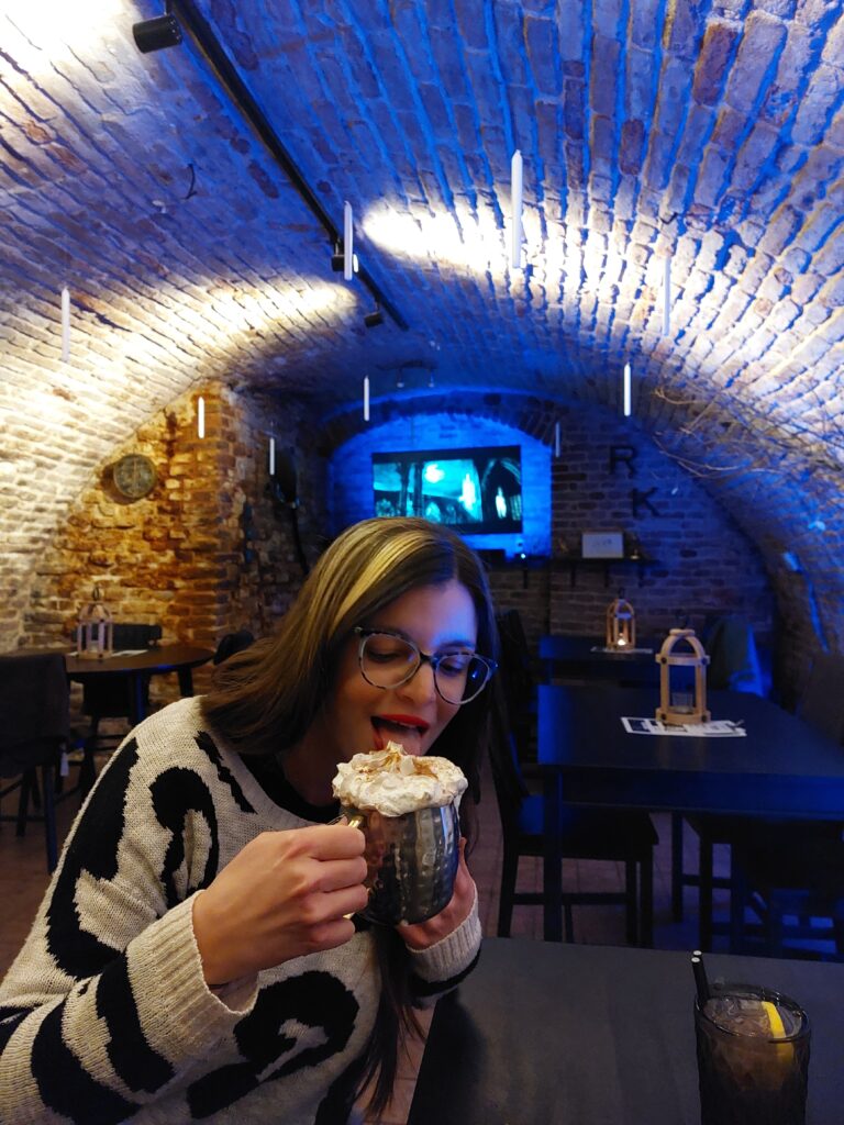 Mirka drinking butterbeer in a basement cafe