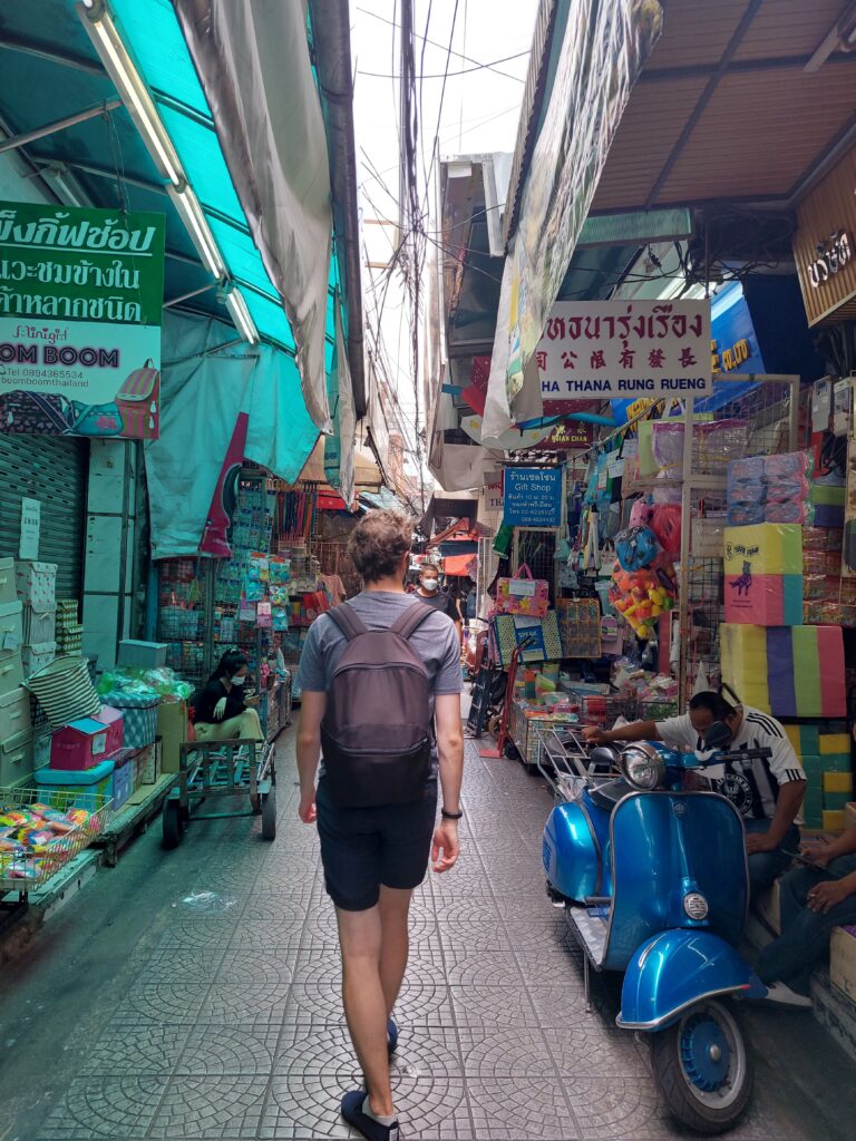 Daniel walking between shops in Chinatown, Bangkok