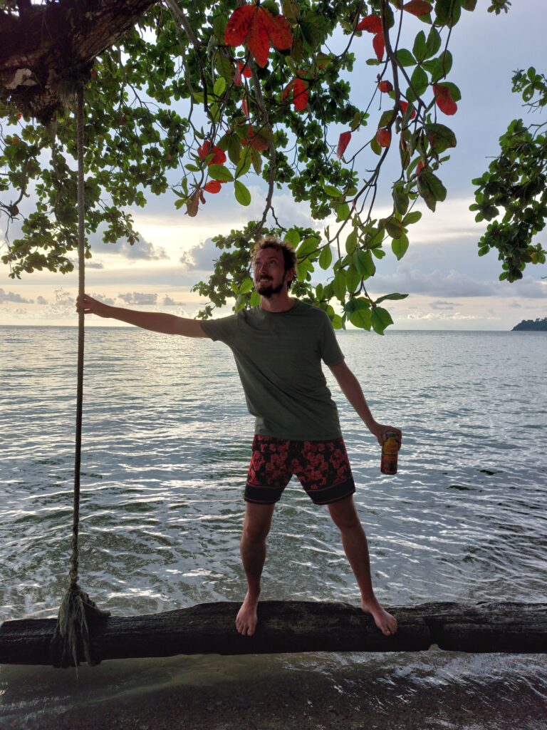 Daniel standing on a tree swing suspended over the sea