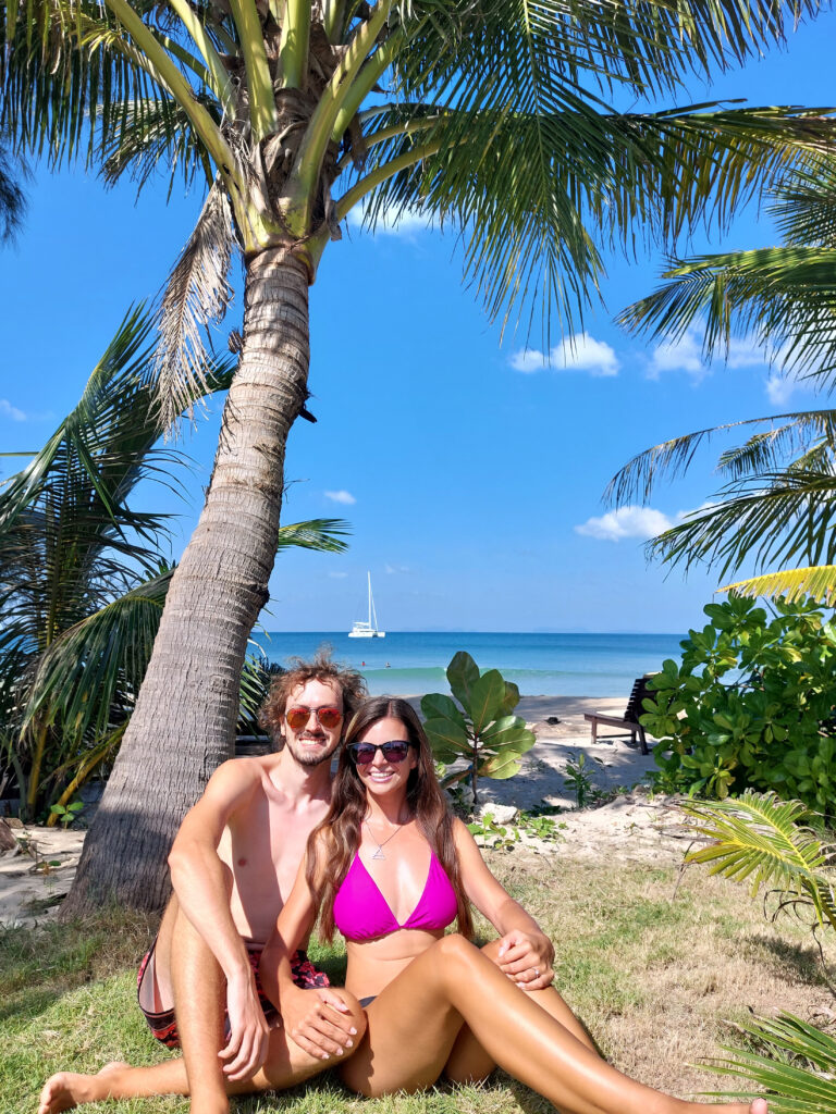 Mirka and Daniel posing in swimwear under a palm tree