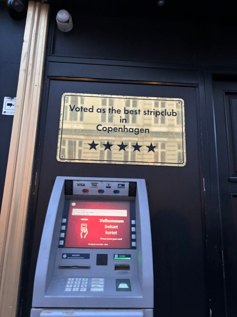 An atm below a sign saying: voted as the best stripclub in Copehagen, 5 stars