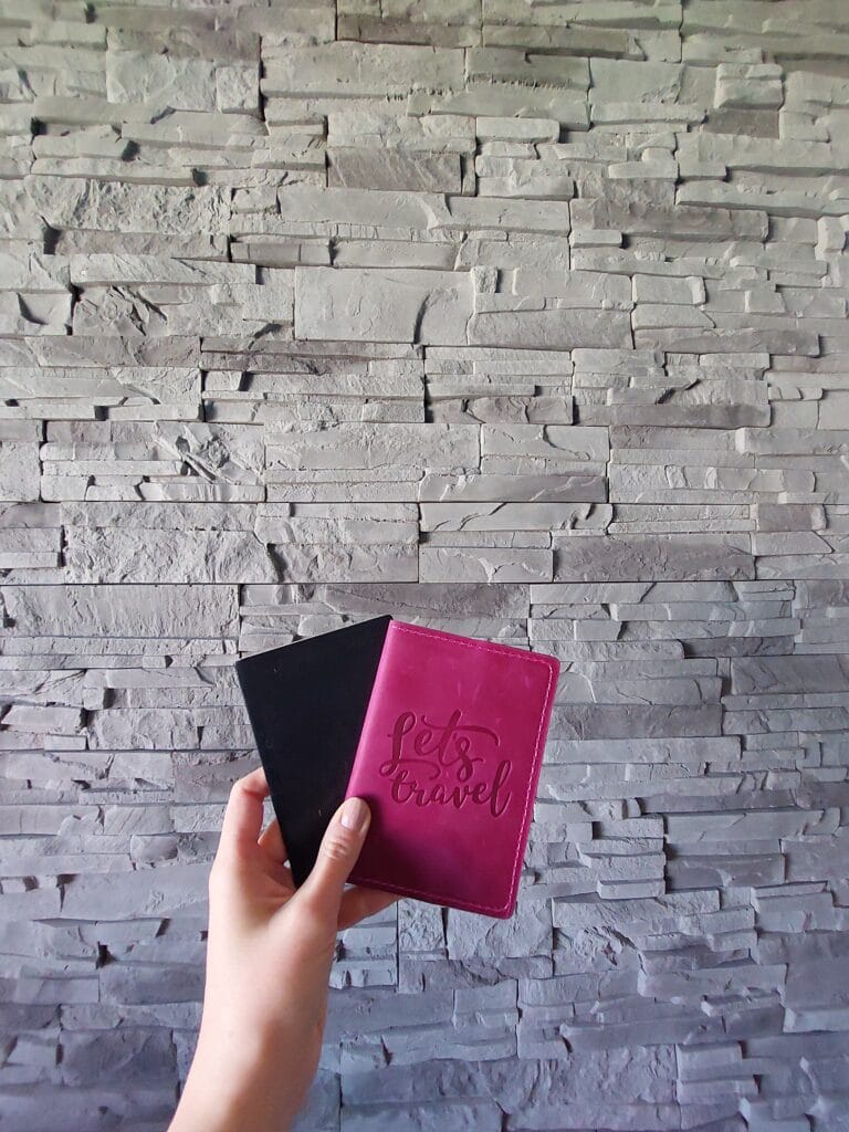 Two passports held up against a stone wall