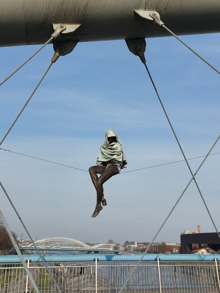 Is Bratislava Worth Visiting? The Truth + Better Alternatives 10 A mysterious statue sitting on a rope on a bridge