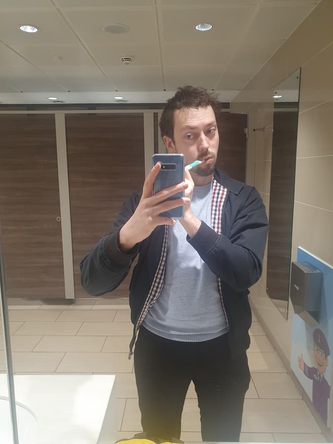 Daniel brushing teeth in an airport bathroom