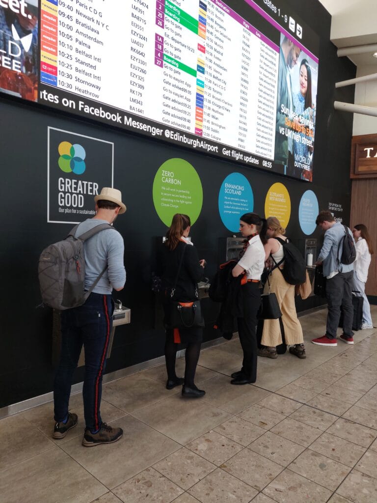 Free Water at Airports: Never Overpay for Water Again 6 A line of people at multiple water refill stations