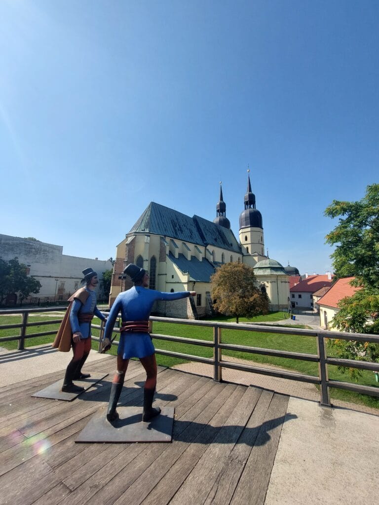 Two statues of characters from olden days and a church