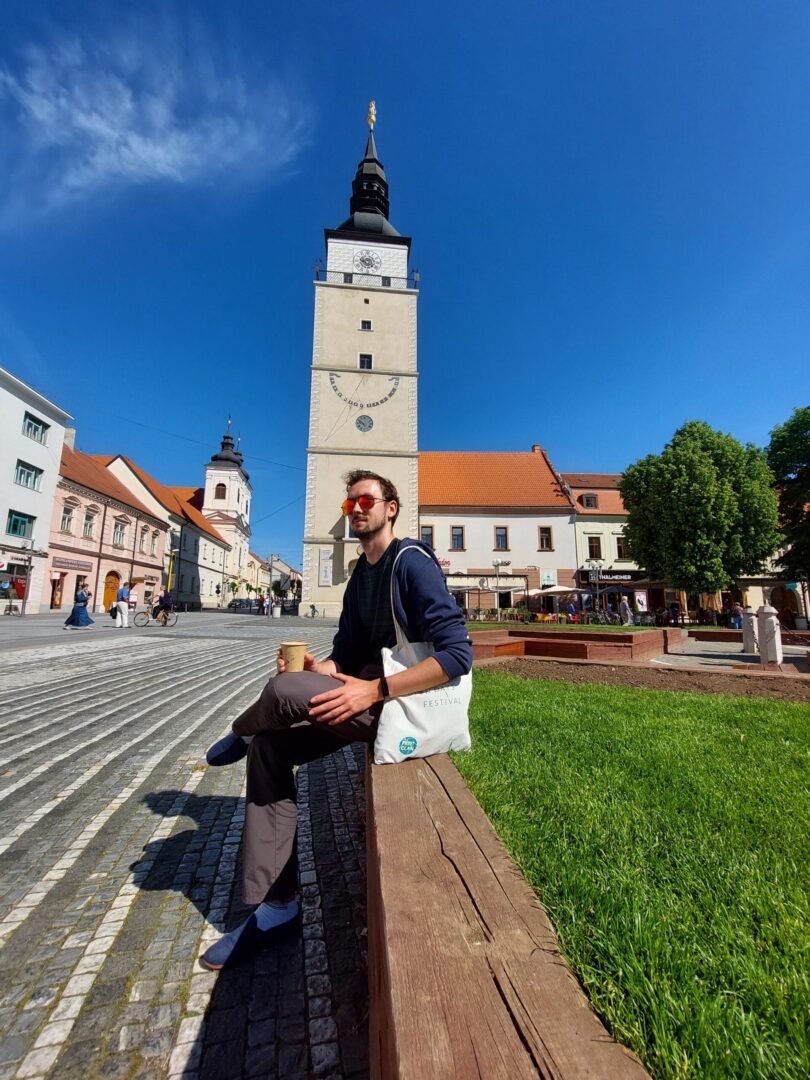 Daniel sitting in front of the Town Tower in Trnava